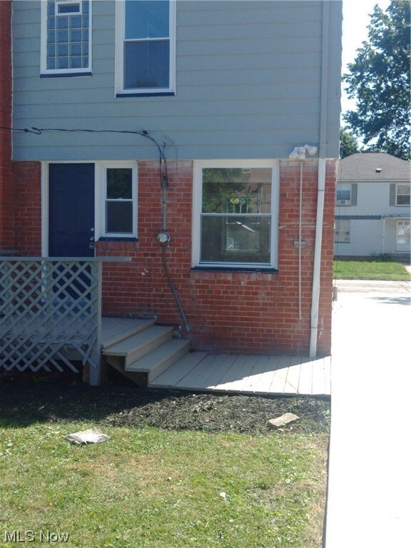 View of exterior rear entry with a lawn and a deck