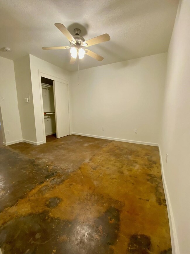  room with a ceiling fan, white walls, and a stain