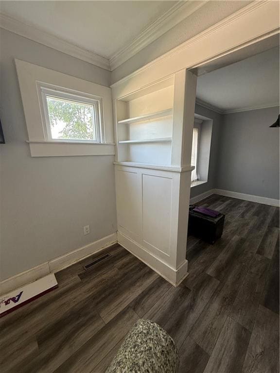 Empty room with ornamental molding, dark wood-style floors, and baseboards