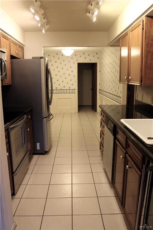 Kitchen featuring sink, light tile patterned flooring, and appliances with stainless steel finishes