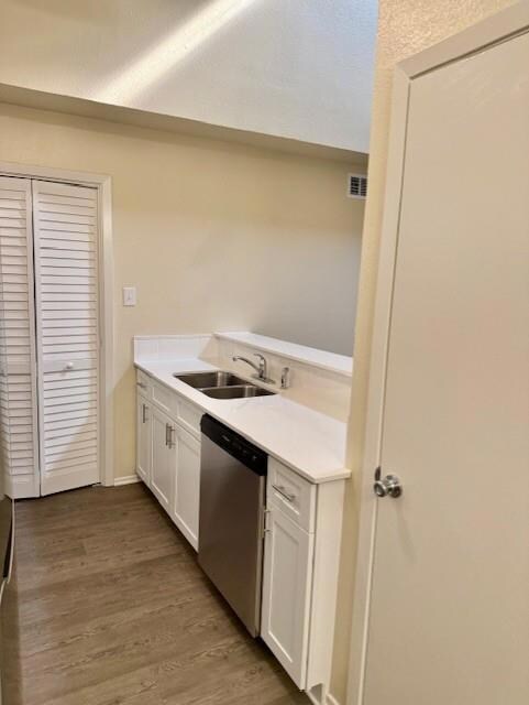 Kitchen featuring white cabinets, dark wood finished floors, dishwasher, light stone counters, and a textured ceiling