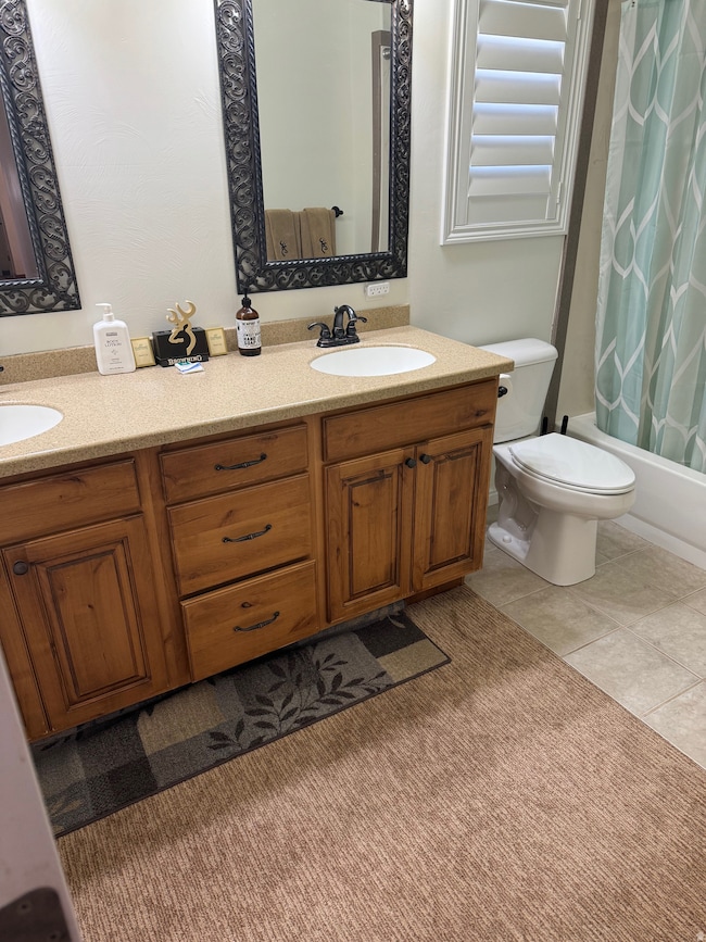 Bathroom featuring double vanity, shower / tub combo with curtain, and light tile patterned floors