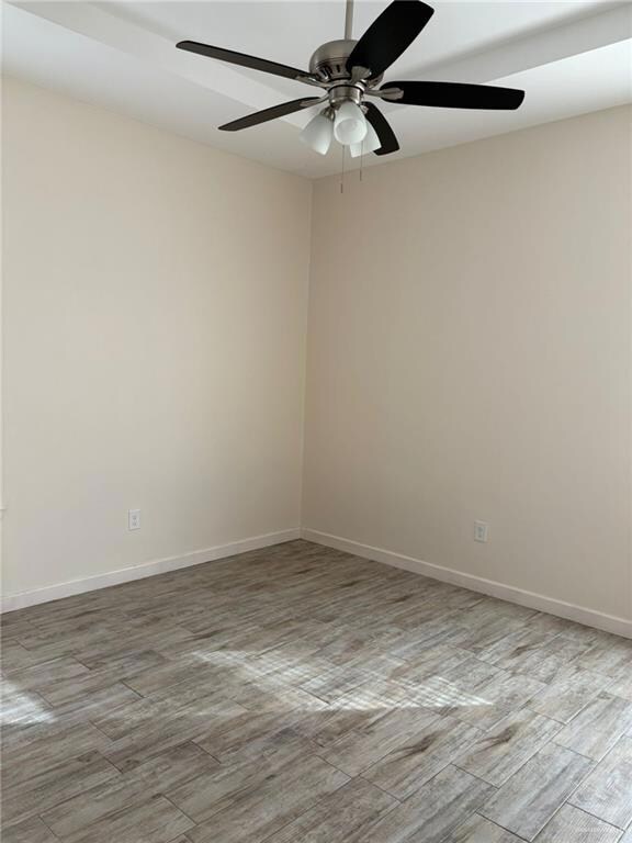 Empty room with wood finish floors and a ceiling fan