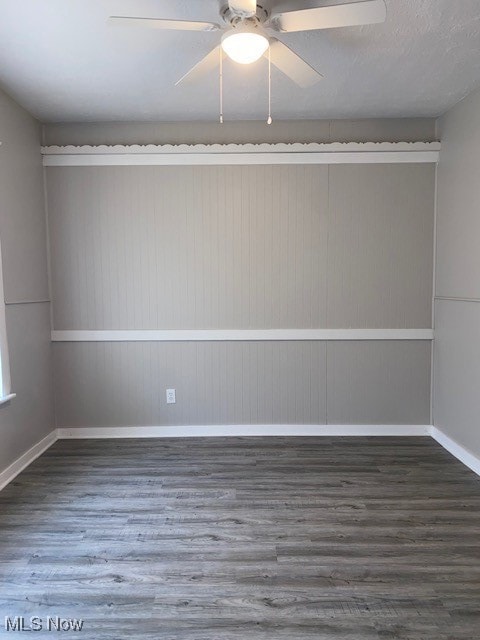 Spare room featuring dark wood-type flooring and ceiling fan