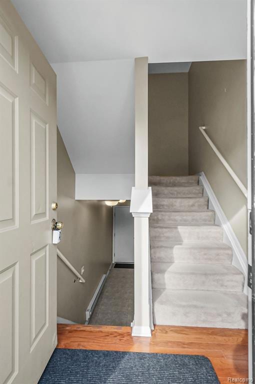 Stairway featuring wood finished floors, baseboard heating, and vaulted ceiling