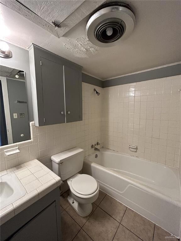Full bath with tile patterned floors, vanity, washtub / shower combination, tile walls, and toilet