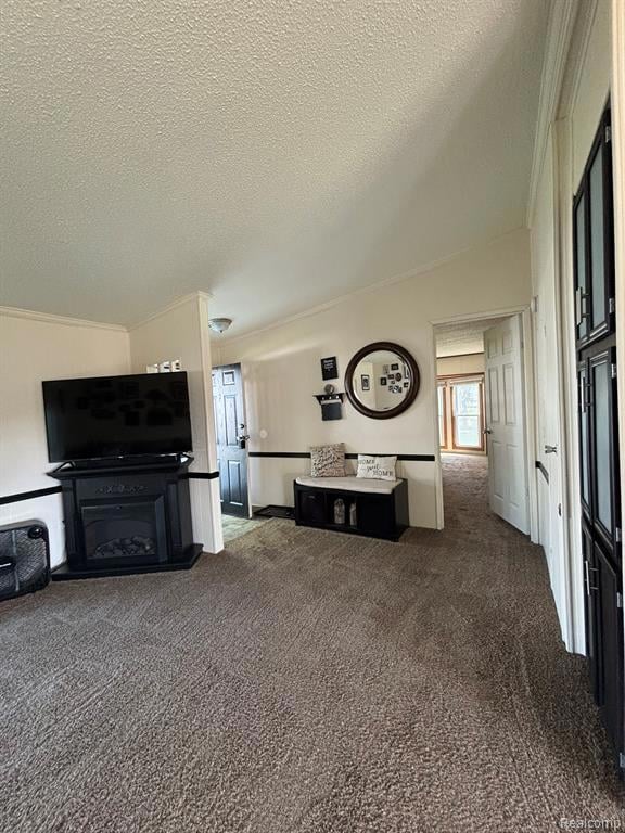 Living area with dark colored carpet, a textured ceiling, crown molding, and a fireplace