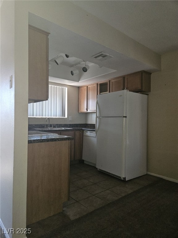 Kitchen featuring white appliances, dark counterto