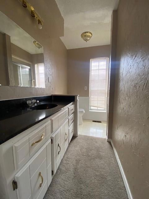 Bathroom featuring toilet, vanity, baseboards, and