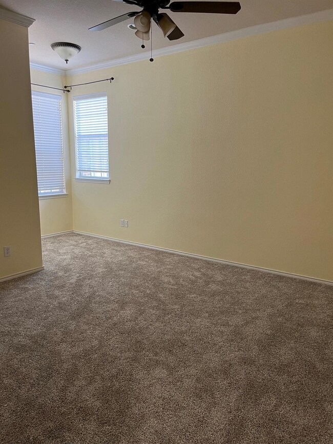 Carpeted empty room featuring ceiling fan and crown molding