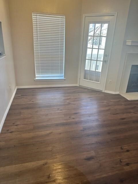 Unfurnished dining area featuring dark wood finished floors and baseboards