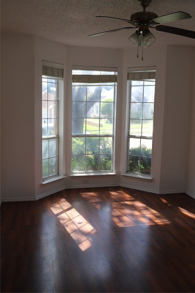 Spare room featuring a ceiling fan, dark wood-style flooring, and a textured ceiling