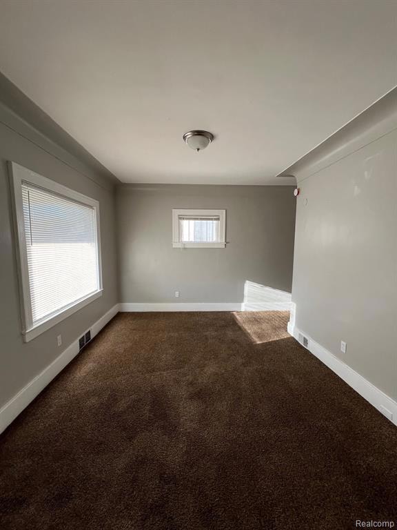 Unfurnished room with dark carpet and baseboards