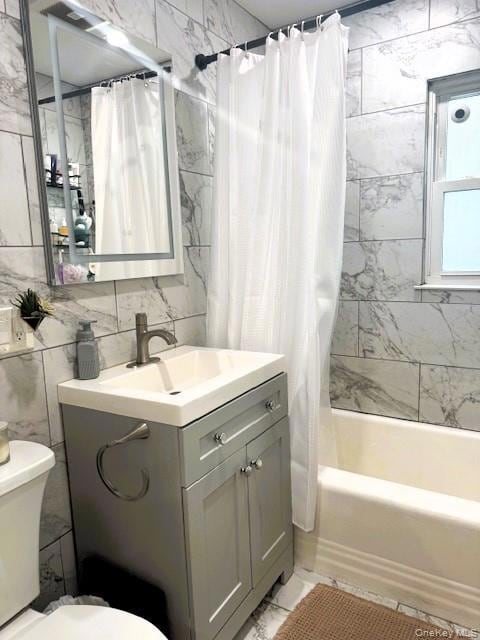 Bathroom featuring tile walls, vanity, and shower / bath combo with shower curtain