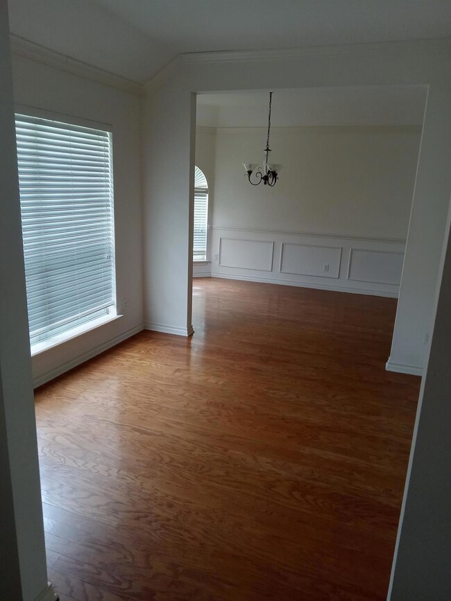 Unfurnished room with plenty of natural light, an inviting chandelier, and hardwood / wood-style floors