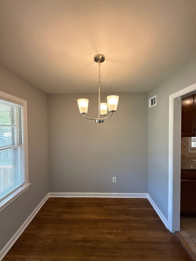 Spare room featuring dark wood-style floors and a chandelier