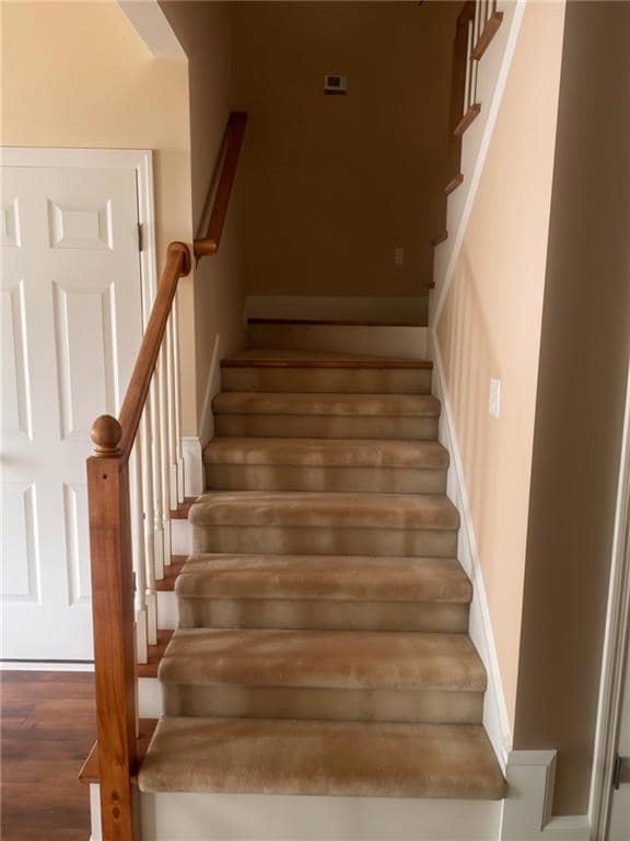 Staircase with wood finished floors and baseboards