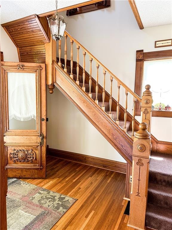 Stairway featuring a textured ceiling, a chandelier, and hardwood / wood-style flooring