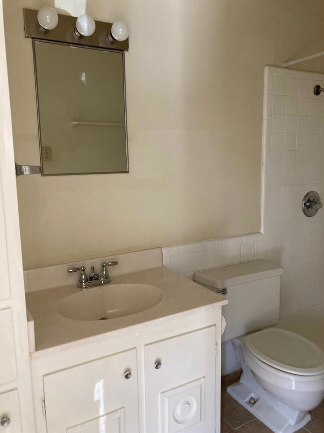 Full bath featuring tiled shower, vanity, tile wa