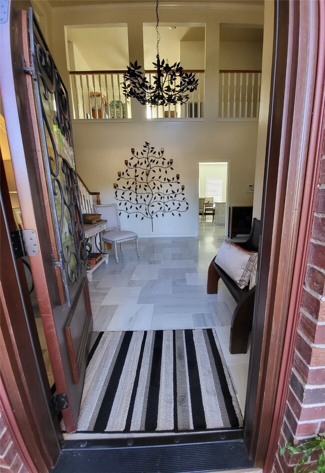 Two story entry, marble flooring and a view to the kitchen and pool in the backyard.