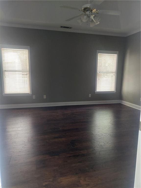Empty room with ornamental molding, dark wood-type flooring, ceiling fan, and baseboards