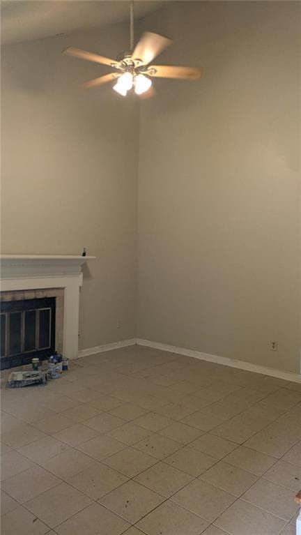 Unfurnished living room featuring a glass covered fireplace, a ceiling fan, and light tile patterned flooring