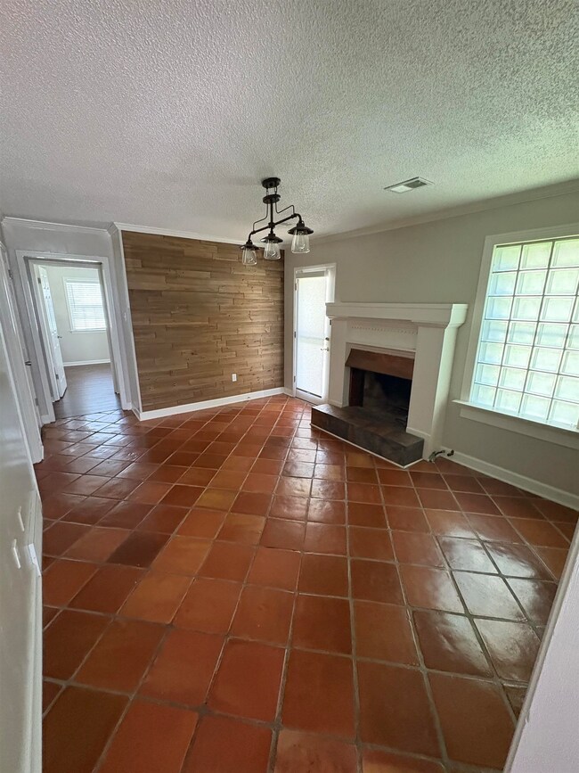 Unfurnished living room featuring a fireplace with raised hearth, a chandelier, dark tile patterned floors, a textured ceiling, and wood walls