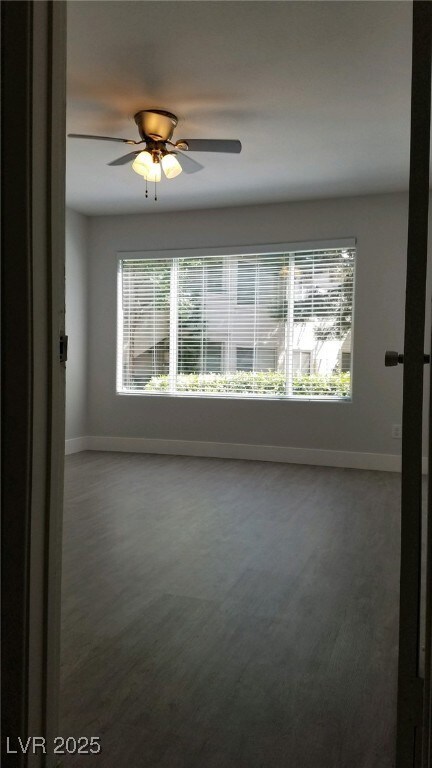 Carpeted empty room featuring baseboards and a ceiling fan