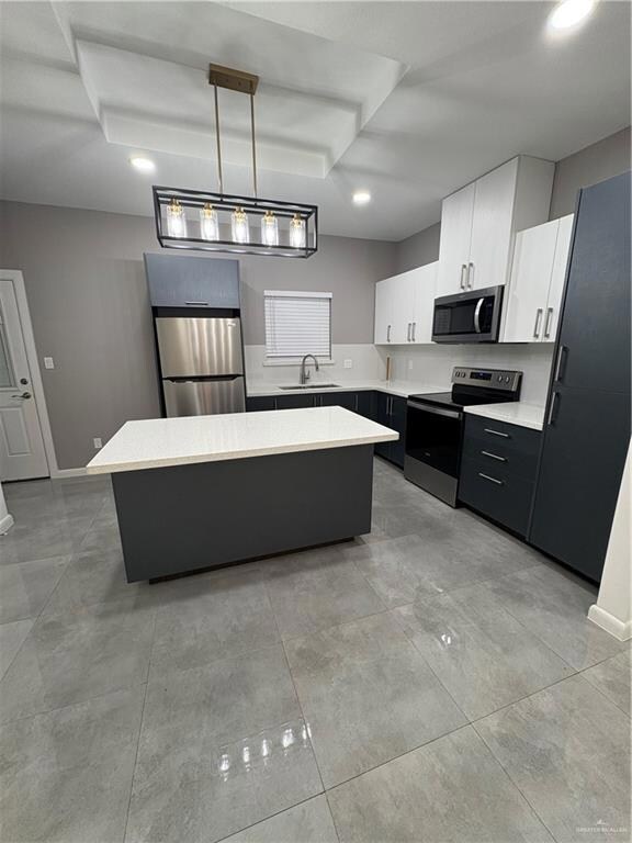 Kitchen featuring range, refrigerator, a sink, a center island, and light countertops
