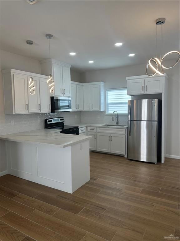 Kitchen with stove, a sink, a peninsula, fridge, and white cabinetry