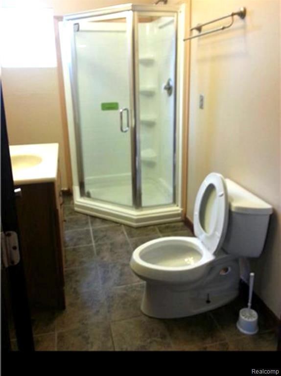 Bathroom with vanity, a stall shower, and dark tile patterned flooring