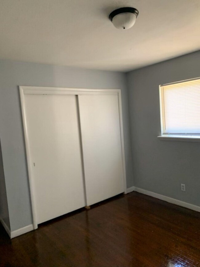 Unfurnished bedroom with dark wood-type flooring a