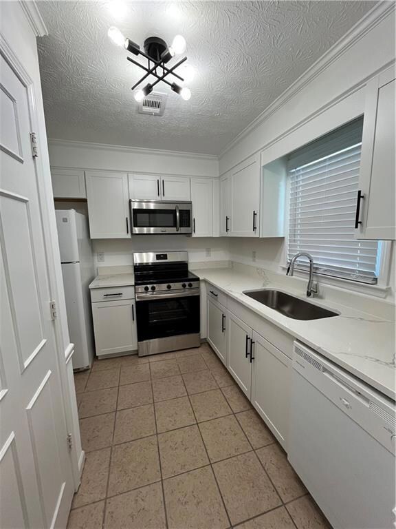 Kitchen with fridge, dishwasher, white cabinetry, 
