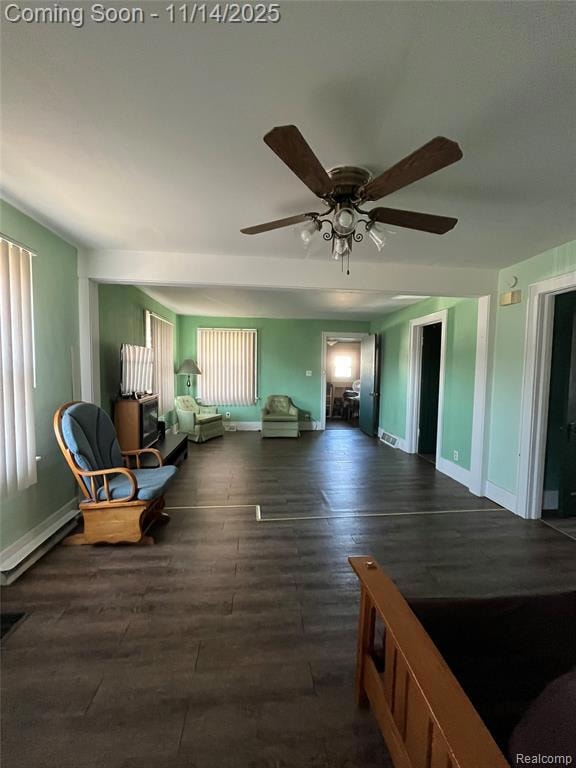 Sitting room with dark wood finished floors, a baseboard heating unit, and a ceiling fan