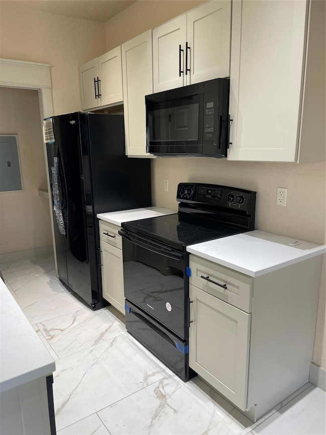Kitchen with black stove, white cabinetry, marble 