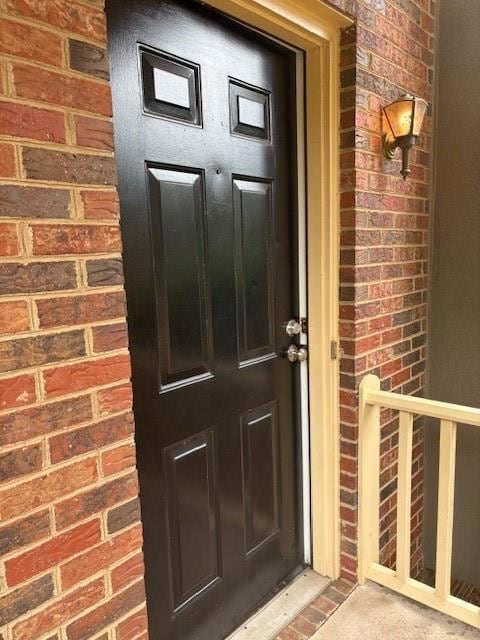 Doorway to property featuring brick siding