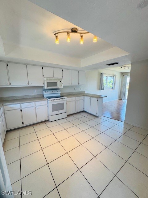 Kitchen with light tile patterned floors, white ap