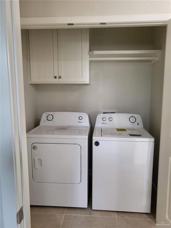 Laundry room featuring washer and dryer, cabinet space, and light tile patterned floors