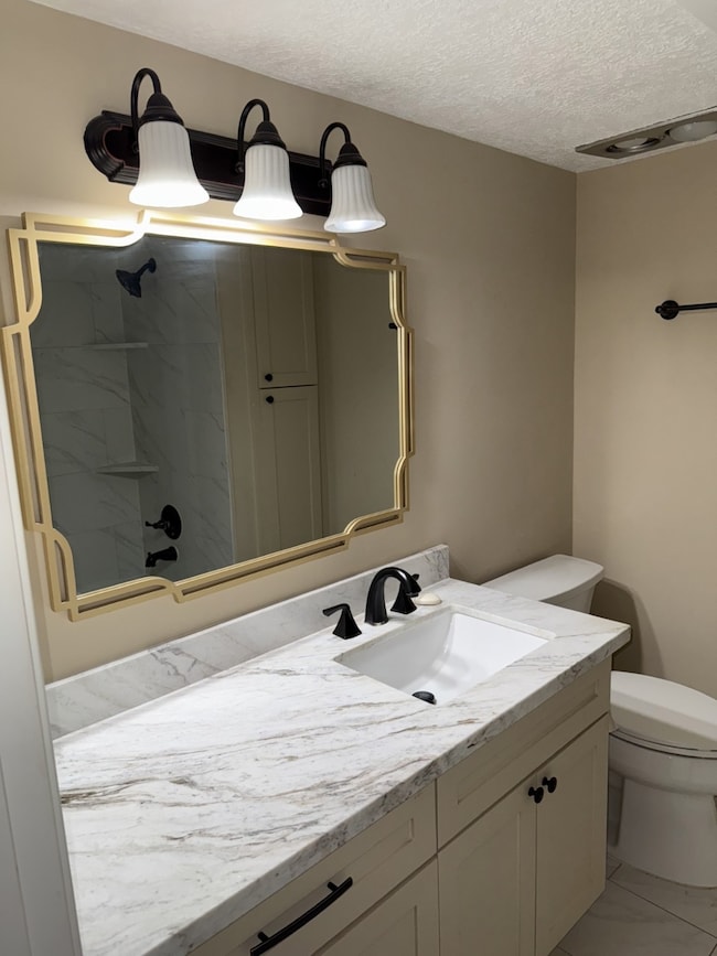 Newly renovated bathroom features marble countertops and tile floor