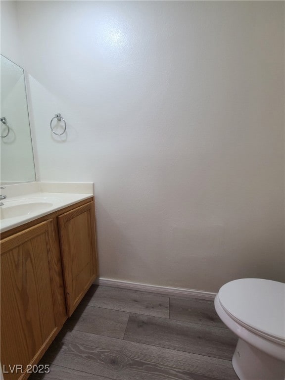 Half bath featuring wood finished floors, vanity,