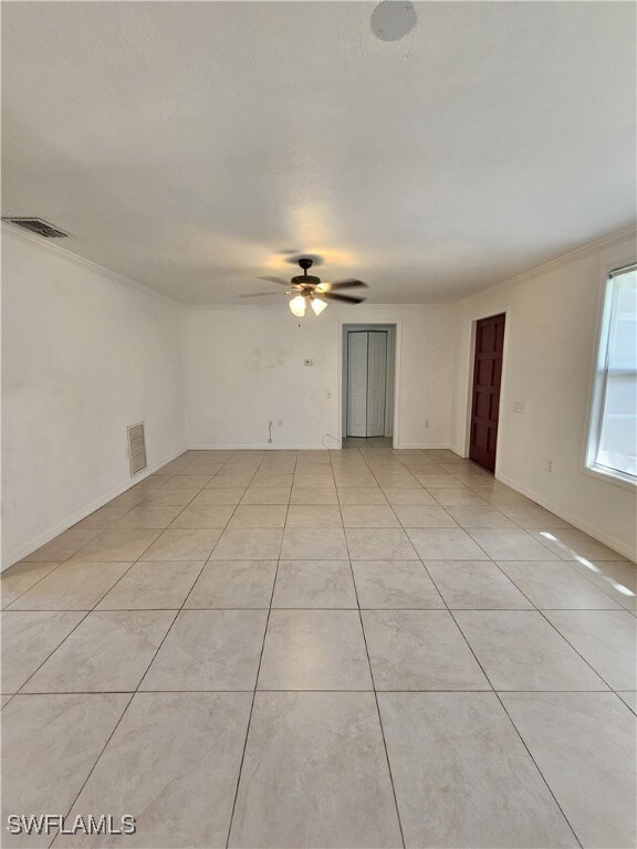 Unfurnished room with a ceiling fan, light tile patterned floors, and crown molding