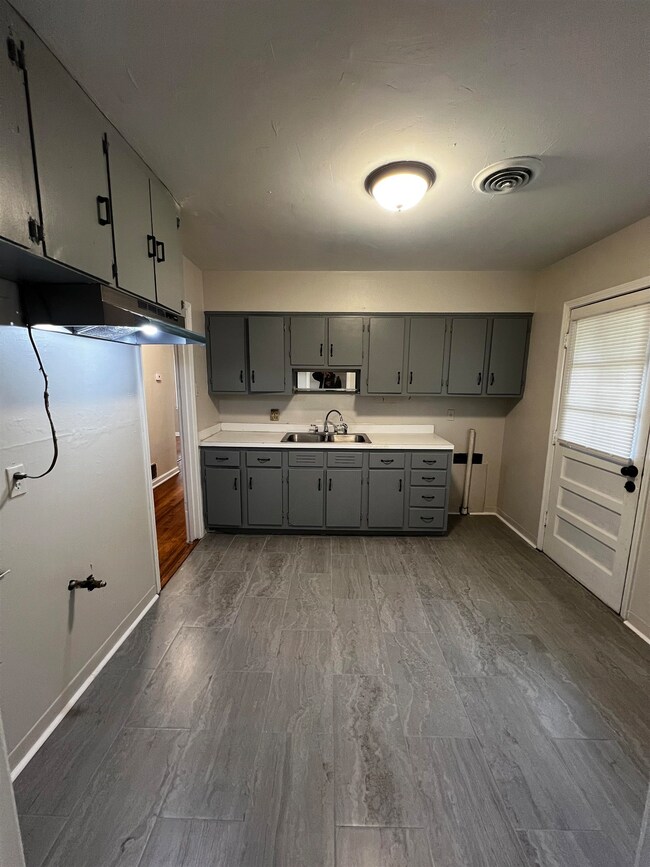 Kitchen featuring gray cabinetry, a sink, baseboar