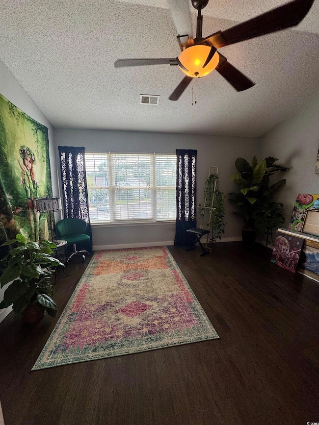 Living room with a textured ceiling, wood finished floors, and ceiling fan
