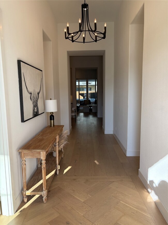 Hallway with a chandelier and parquet floors