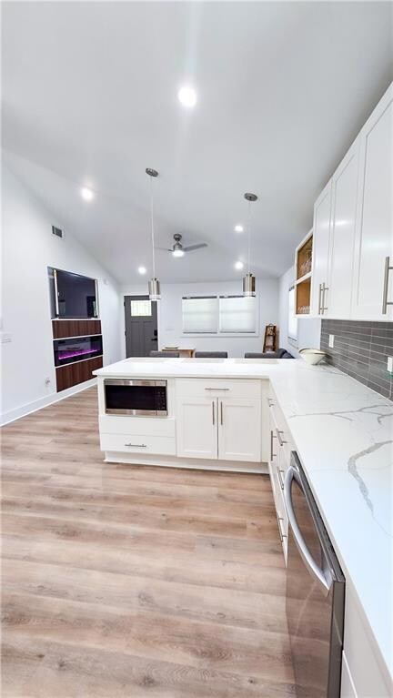 Kitchen featuring dishwasher, white cabinetry, recessed lighting, light stone countertops, and decorative light fixtures