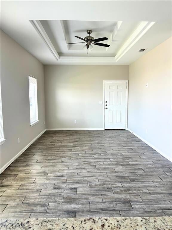Spare room featuring a ceiling fan, wood finished floors, and a raised ceiling