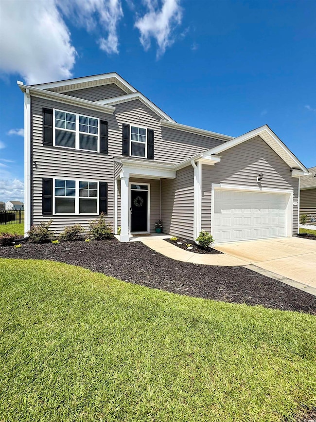 Traditional-style house with a garage, concrete driveway, and a front yard