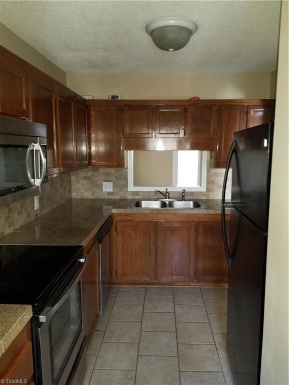 Wood cabinets, tile counter, backsplash, and floors in kitchen