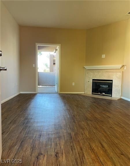 Unfurnished living room with dark wood-style floors and a premium fireplace