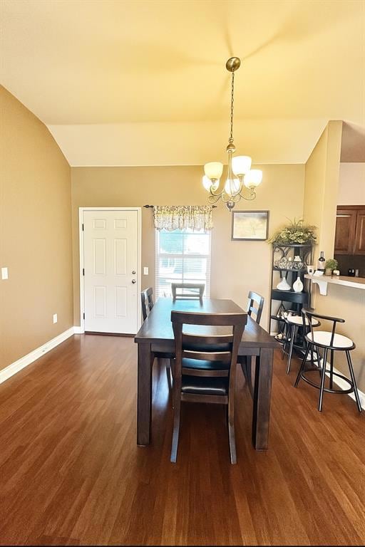 Dining room with wood finished floors, a chandelier, and lofted ceiling
